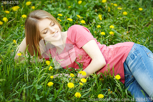 Image of Spring girl lying on the field of dandelions