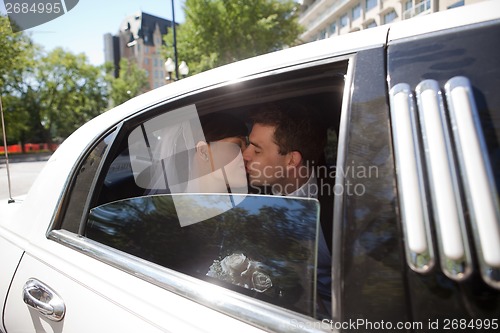 Image of Newlywed Couple Kissing In Limousine