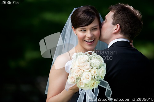 Image of Groom Kissing Bride on Ear