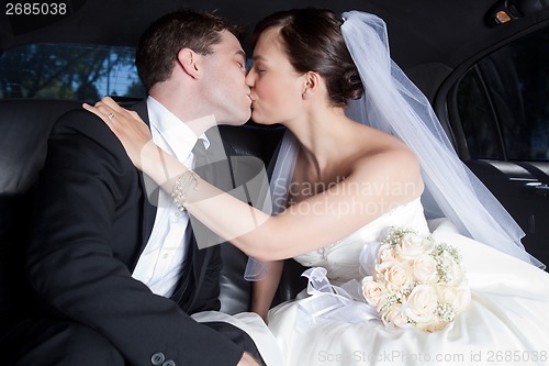 Image of Newlywed Couple Kissing In Limousine