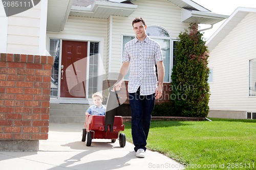 Image of Father Pulling Son Sitting Inside Wagon