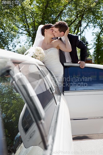 Image of Newlywed Couple Standing Beside Limousine