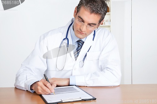 Image of Male Doctor Writing on Clipboard