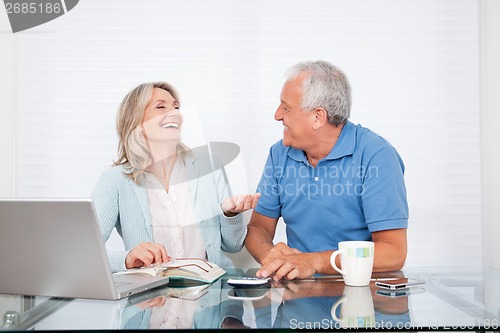 Image of Couple At Dining Table Working on Laptop