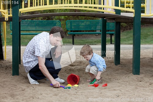 Image of Father And Son Playing At Playground In Sand