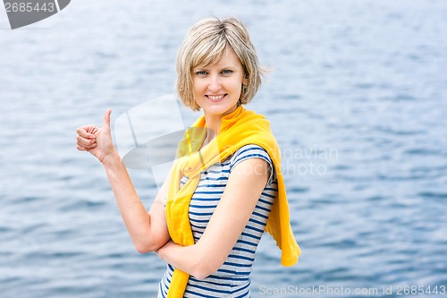 Image of Middle age woman outdoors gesturing thumb up