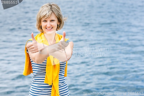 Image of Middle age woman outdoors gesturing thumb up