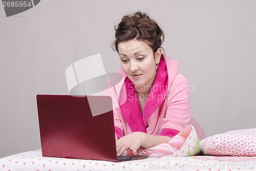 Image of The surprised girl in bed works for laptop