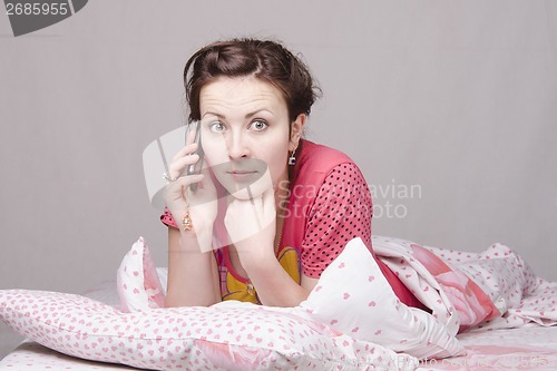 Image of girl on bed in shock from talking phone