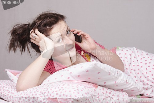 Image of Girl talking on the phone, lying in bed