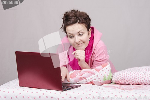 Image of girl on bed looking with interest at laptop