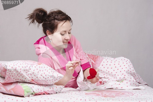 Image of Girl in bed considers a gift ring