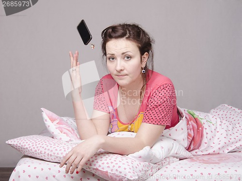 Image of Young girl in the bed and threw phone