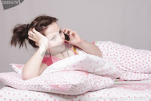Image of young girl talking on phone lying in bed