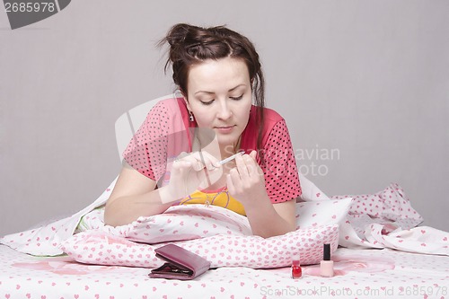 Image of Girl enthusiastically saws, nails lying in bed