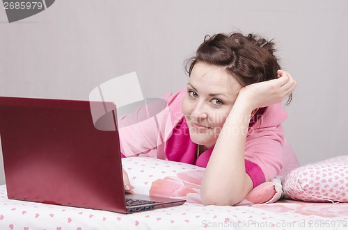 Image of Happy girl in bed works for laptop