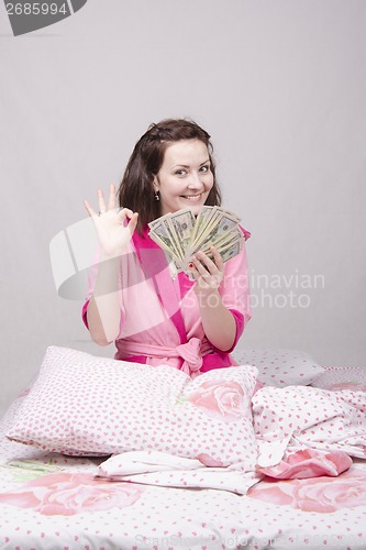 Image of Young girl sitting in bed with a bundle of money