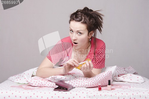Image of Girl takes care of the nails lying in bed