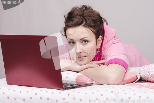 Image of Thoughtful girl in bed works for laptop