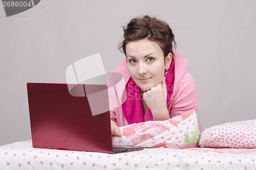 Image of The girl lying in bed works for laptop