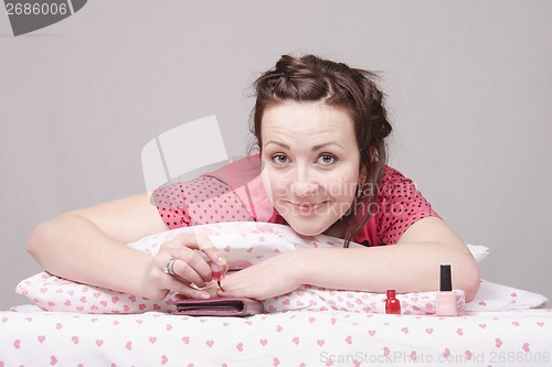 Image of Girl in bed paints nails