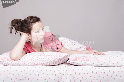 Image of young girl is sad lying in bed