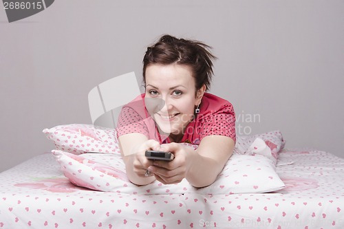 Image of young girl is watching TV in bed