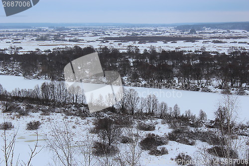 Image of winter frozen river and forest on the background