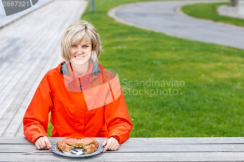 Image of Happy woman eating crab outdoors