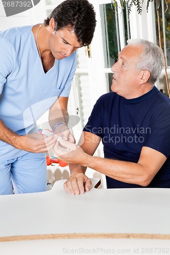 Image of Male Nurse Checking Sugar Level Of Senior Man