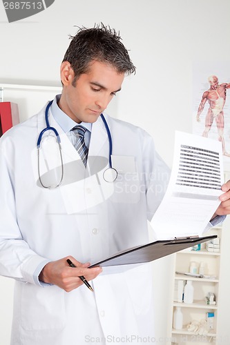 Image of Male Doctor Looking at Clipboard