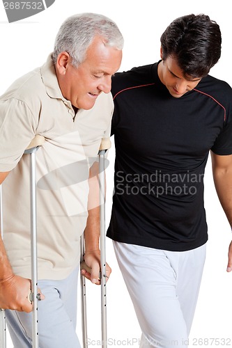 Image of Trainer Helping Senior Man With Crutches