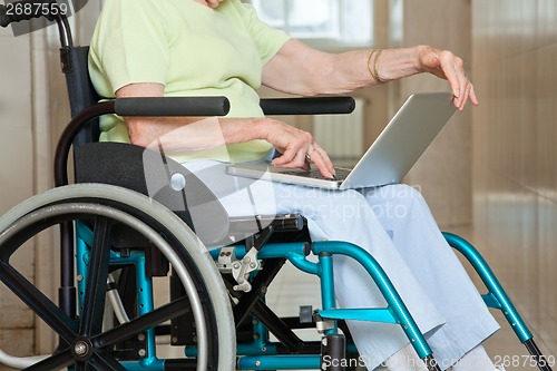 Image of Senior Woman Sitting In Wheelchair Using Laptop