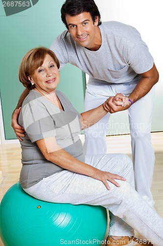Image of Therapist Helping Senior Woman Sitting On Fitness Ball