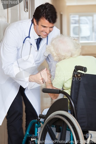 Image of Doctor Assisting Senior Woman In Wheelchair