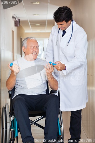 Image of Doctor Giving Hand Weights To The Senior Man Sitting In a Wheelc