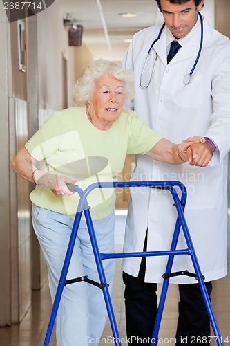 Image of Doctor Showing Way To The Patient Using Walker