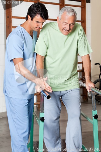 Image of Therapist Assisting Senior Man To Walk With The Support Of Bars