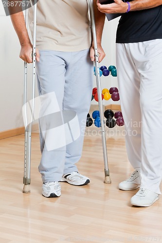 Image of Man Holding Crutches Standing By Trainer