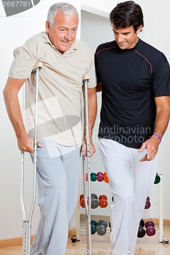 Image of Trainer Helping Senior Man To Walk