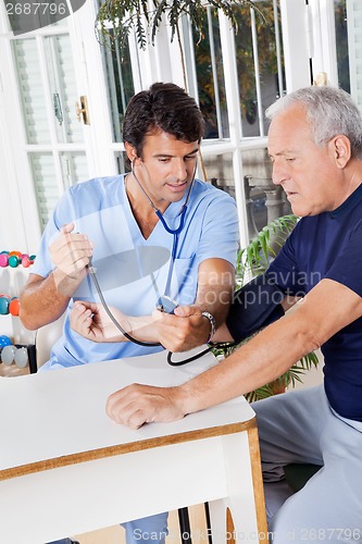 Image of Male Nurse Checking Blood Pressure Of a Senior Patient