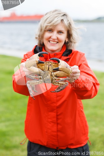 Image of Happy woman showing alive crab outdoors