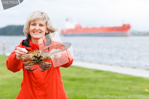 Image of Happy woman showing alive crab outdoors