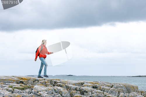 Image of Woman hiker walking on rock against sea background