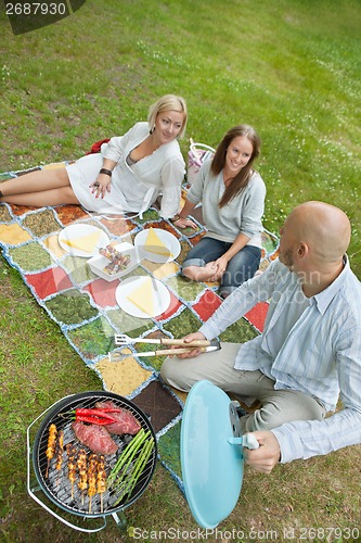 Image of Friends Eating Food At An Outdoor Picnic