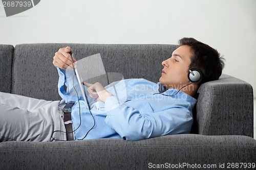 Image of Relaxed Man Listening Music On Digital Tablet