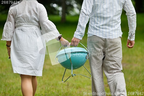 Image of Couple Walking With Portable Barbeque