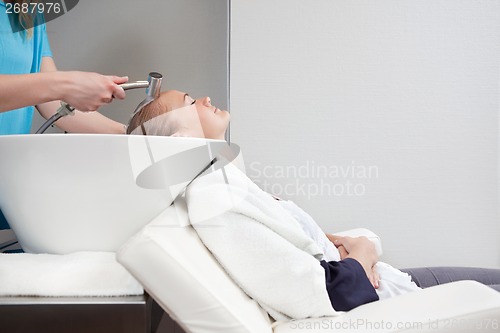 Image of Young Woman Having Hair Rinsed