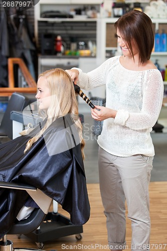 Image of Stylist Curling Womans Hair