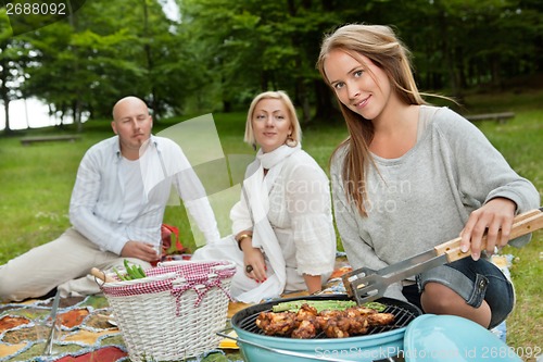 Image of Female Cooking Meat On Portable Barbecue